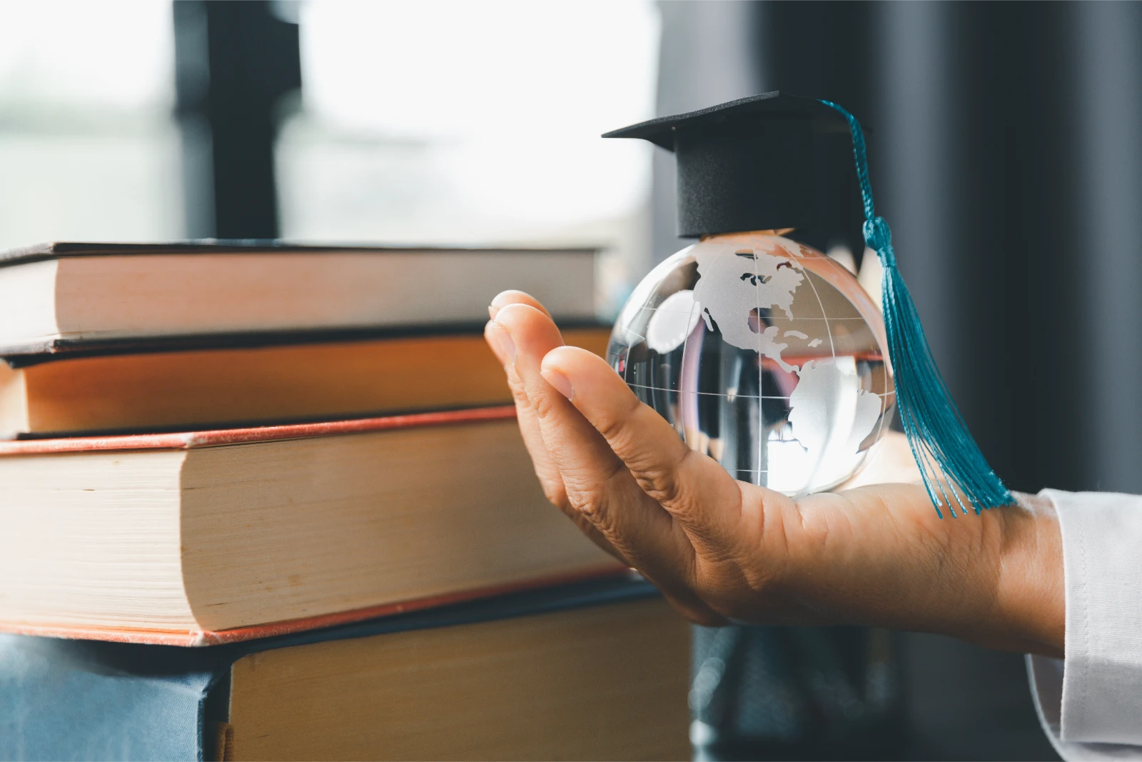 How to use Ecctis to prove your English language ability for a UK visa represented by a glass globe with a graduation cap on it, held by a person next to some books.